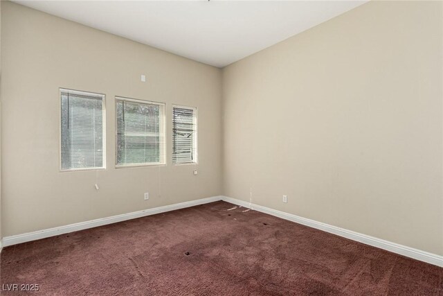 unfurnished room with dark carpet and baseboards