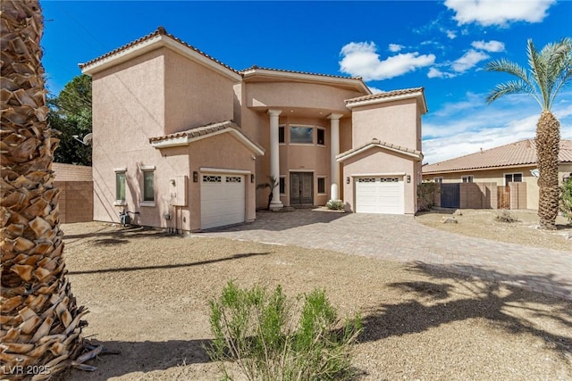 mediterranean / spanish-style house featuring a garage, fence, a tiled roof, and stucco siding