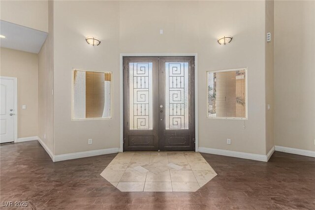 foyer entrance with french doors, a high ceiling, and baseboards