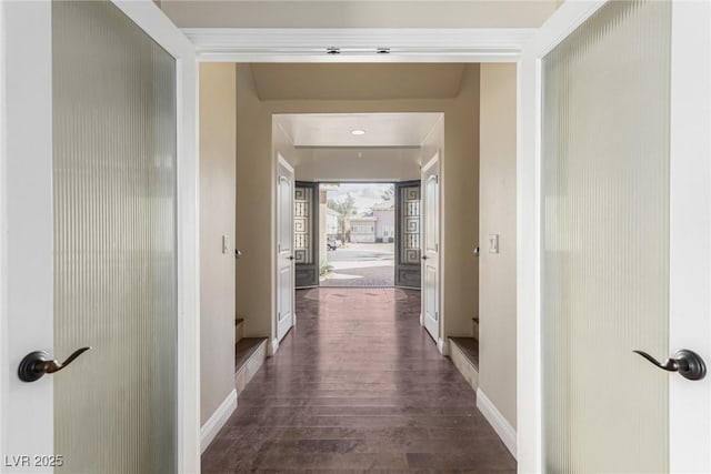 corridor featuring dark wood-type flooring and baseboards