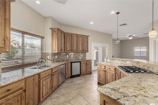 kitchen featuring visible vents, appliances with stainless steel finishes, hanging light fixtures, a sink, and backsplash