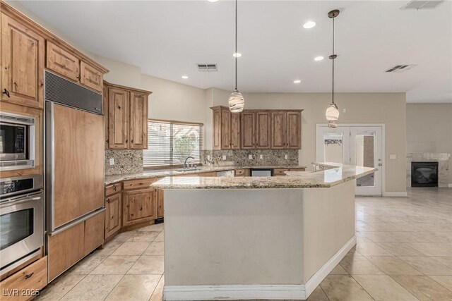 kitchen with light tile patterned flooring, visible vents, a sink, and built in appliances