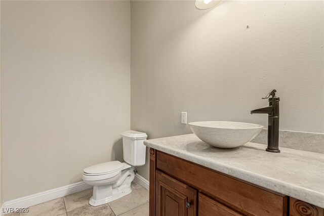 half bath with toilet, tile patterned flooring, baseboards, and vanity