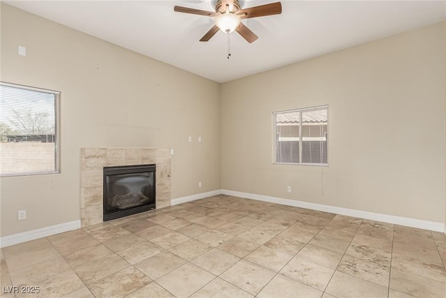 unfurnished living room featuring a tiled fireplace, a ceiling fan, and baseboards