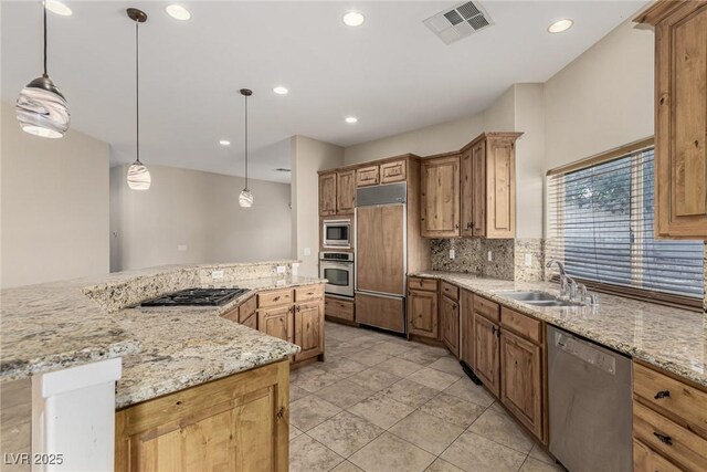 kitchen featuring visible vents, decorative backsplash, a spacious island, built in appliances, and a sink