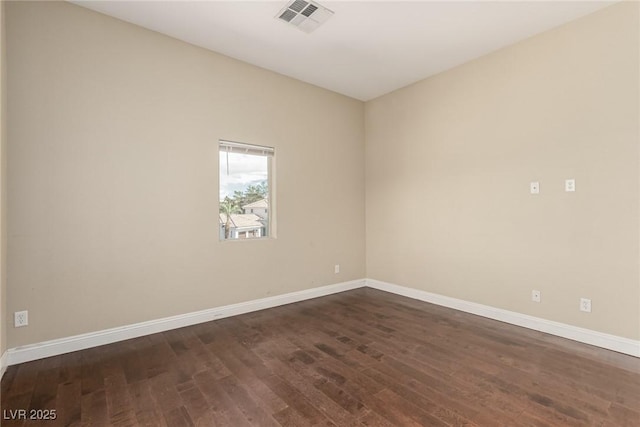 empty room with dark wood-style flooring, visible vents, and baseboards