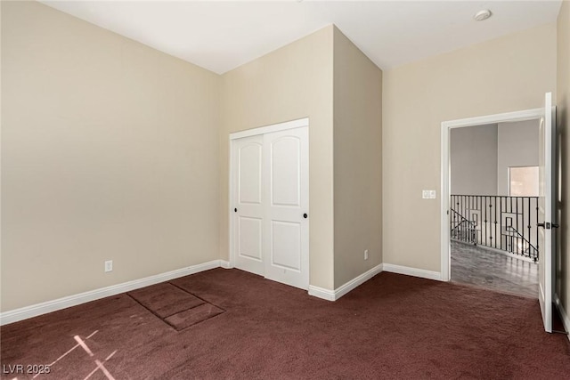 unfurnished bedroom with dark carpet and baseboards