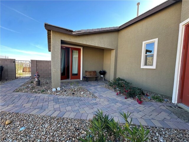 doorway to property with a patio, fence, a gate, and stucco siding