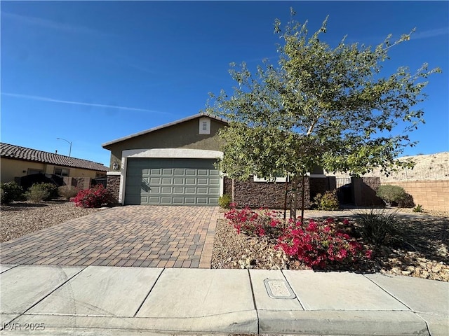 view of front facade with decorative driveway, an attached garage, fence, and stucco siding