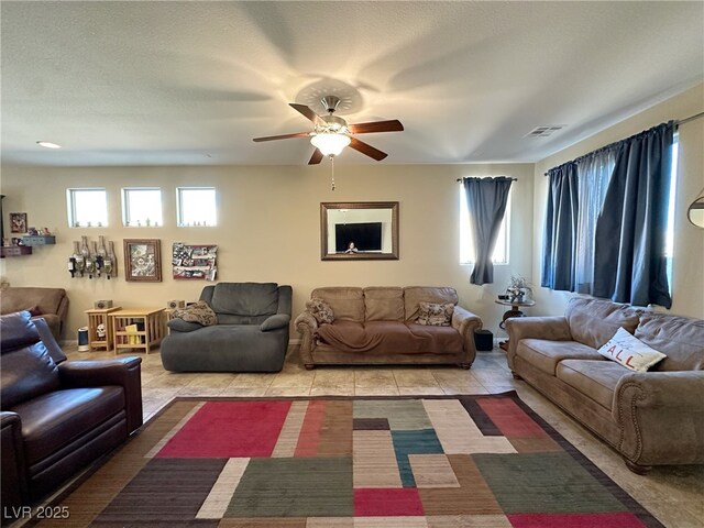 tiled living room with a ceiling fan, visible vents, and a textured ceiling