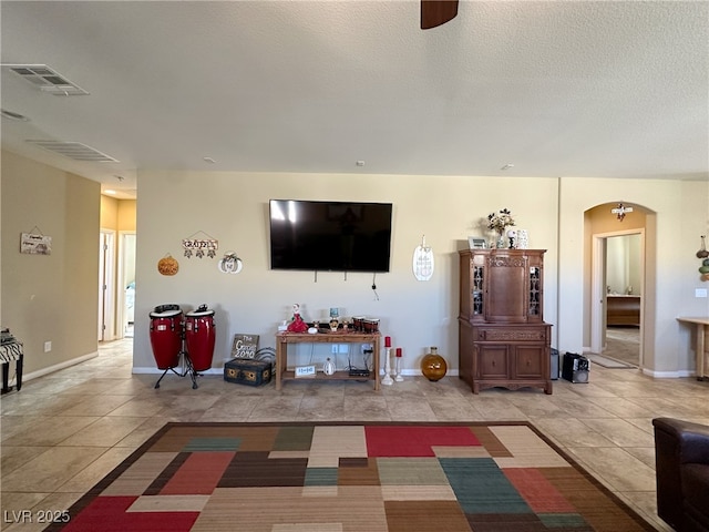 living area with arched walkways, tile patterned flooring, visible vents, and a textured ceiling