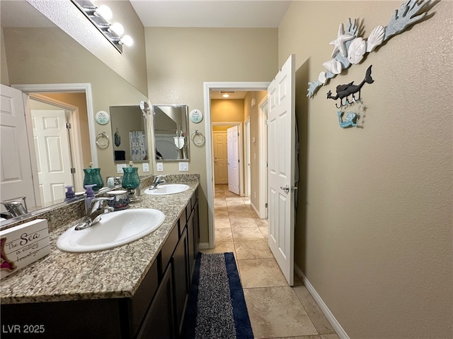 full bath featuring double vanity, tile patterned floors, a sink, and baseboards