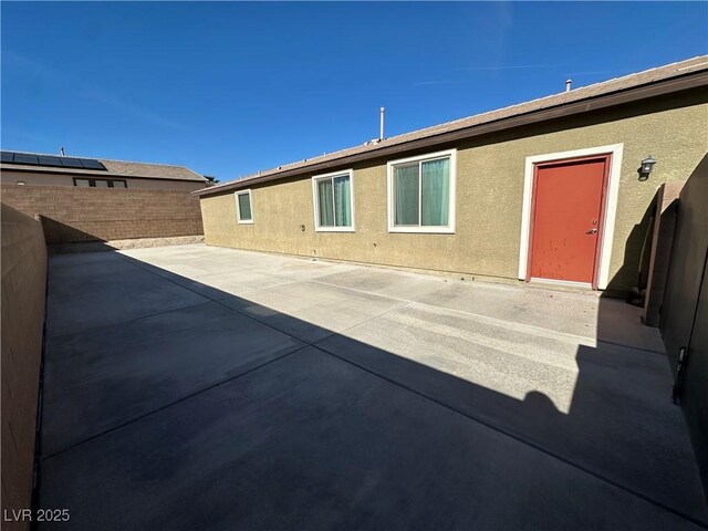 back of house with a fenced backyard, a patio, and stucco siding