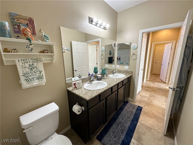 full bathroom featuring baseboards, a sink, toilet, and double vanity