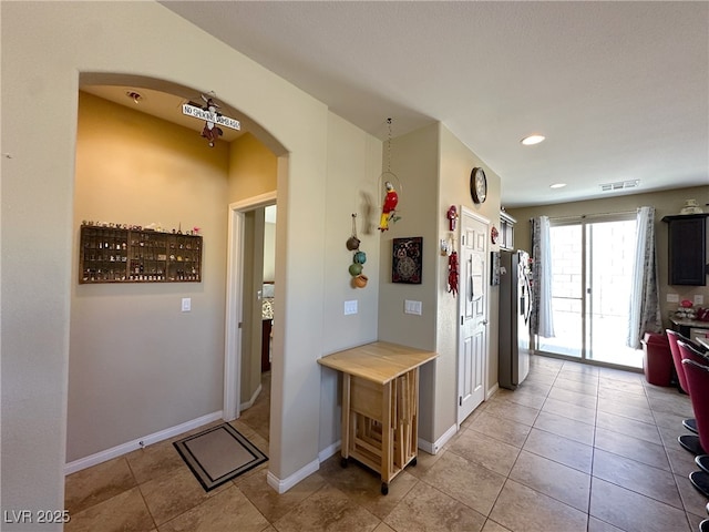 interior space with stainless steel fridge, visible vents, arched walkways, and light tile patterned flooring