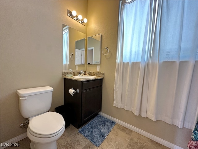 bathroom featuring toilet, baseboards, and vanity