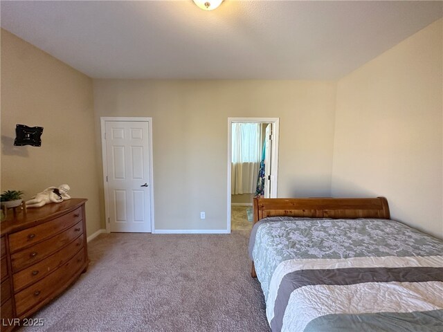 carpeted bedroom featuring a walk in closet and baseboards