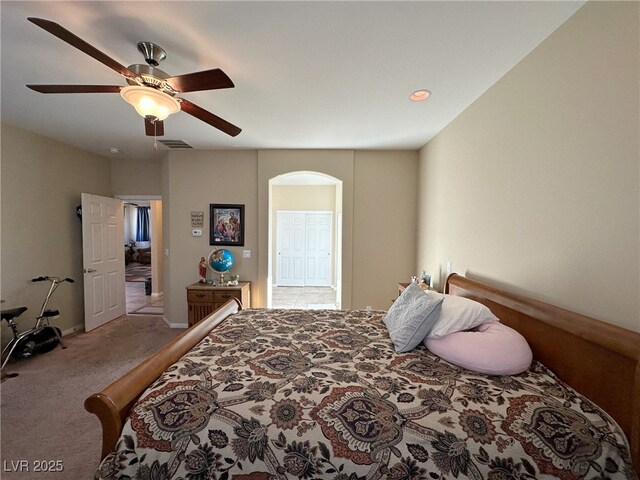 carpeted bedroom featuring ceiling fan, visible vents, and arched walkways