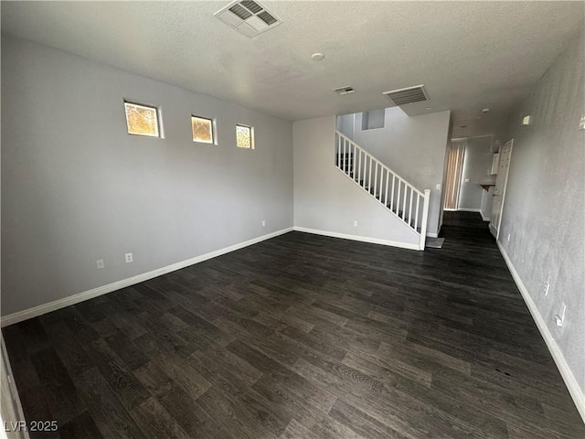 interior space featuring stairway, dark wood-type flooring, visible vents, and a textured ceiling