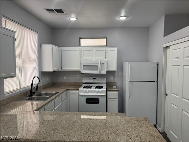 kitchen with visible vents, a healthy amount of sunlight, white cabinets, white appliances, and a sink