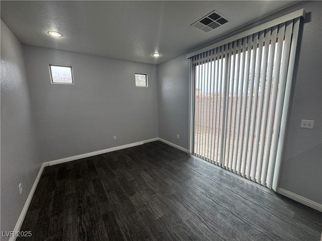 unfurnished room with visible vents, baseboards, and dark wood finished floors