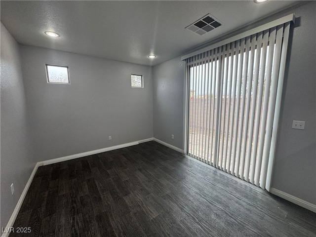 unfurnished room featuring recessed lighting, dark wood-style floors, visible vents, and baseboards