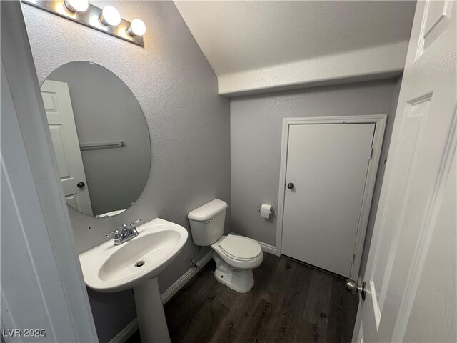 bathroom featuring toilet, baseboards, and wood finished floors