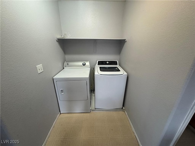 clothes washing area featuring baseboards, laundry area, separate washer and dryer, tile patterned floors, and a textured wall