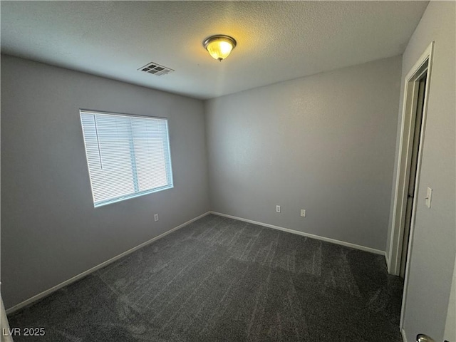 unfurnished room with dark colored carpet, visible vents, baseboards, and a textured ceiling