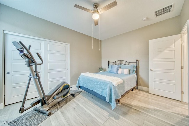 bedroom with a closet, visible vents, a ceiling fan, light wood-type flooring, and baseboards