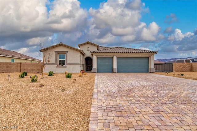 view of front facade featuring a garage, fence, decorative driveway, a gate, and stucco siding