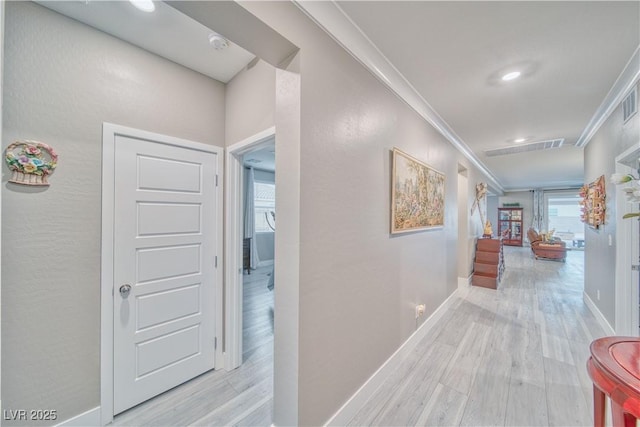 corridor with ornamental molding, wood finished floors, visible vents, and baseboards