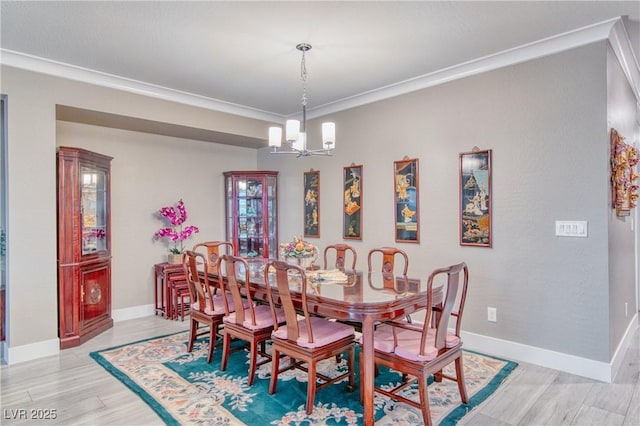 dining space featuring a chandelier, ornamental molding, light wood-style flooring, and baseboards