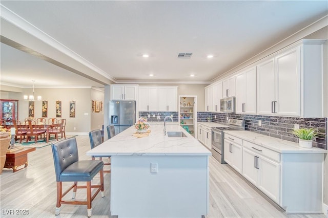 kitchen featuring white cabinets, a kitchen bar, visible vents, and stainless steel appliances