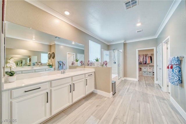 bathroom featuring a stall shower, visible vents, wood finished floors, a spacious closet, and crown molding