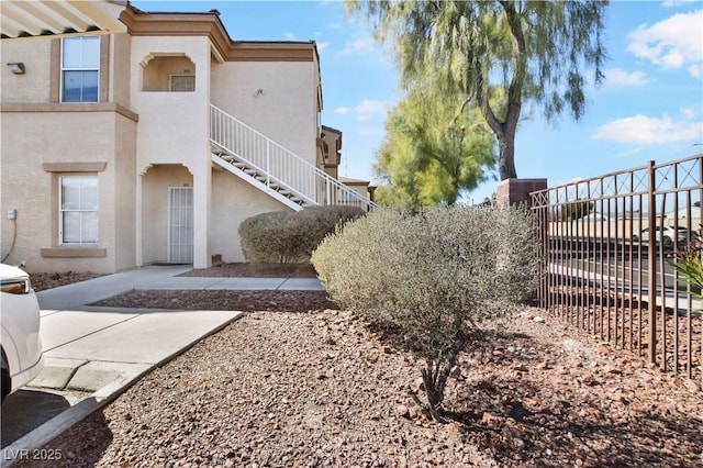 exterior space featuring stairs, fence, and stucco siding