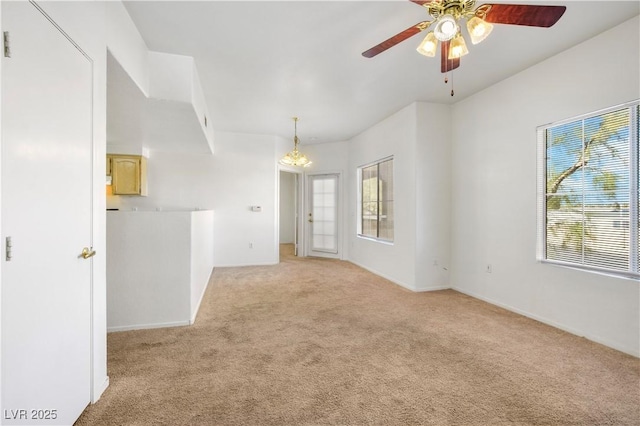 empty room featuring light carpet and ceiling fan with notable chandelier