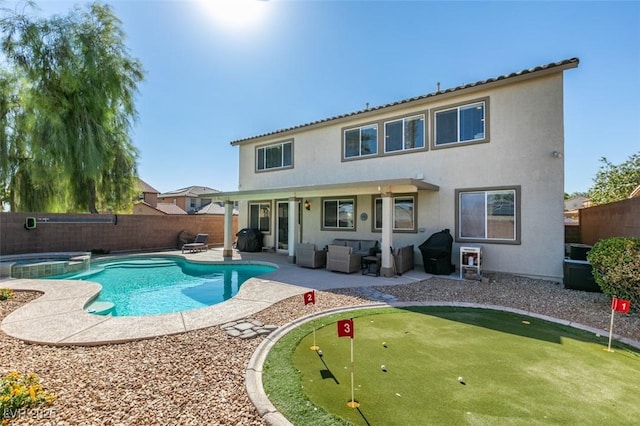 rear view of house featuring a putting green, a patio area, a fenced backyard, outdoor lounge area, and stucco siding