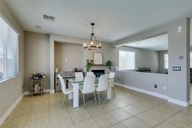 dining room featuring light tile patterned floors, baseboards, visible vents, and a chandelier