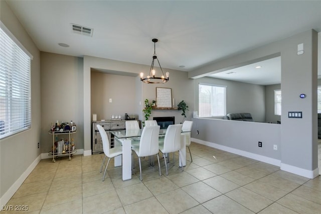 dining space with a chandelier, light tile patterned flooring, and baseboards
