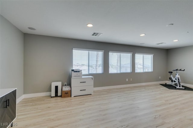 workout area with light wood-type flooring, plenty of natural light, and baseboards