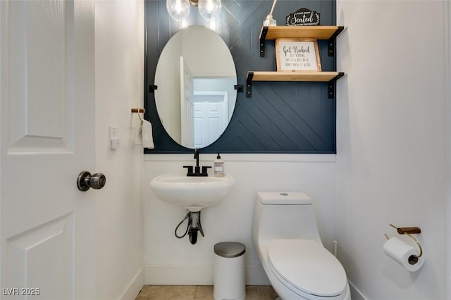 bathroom featuring toilet, baseboards, and tile patterned flooring