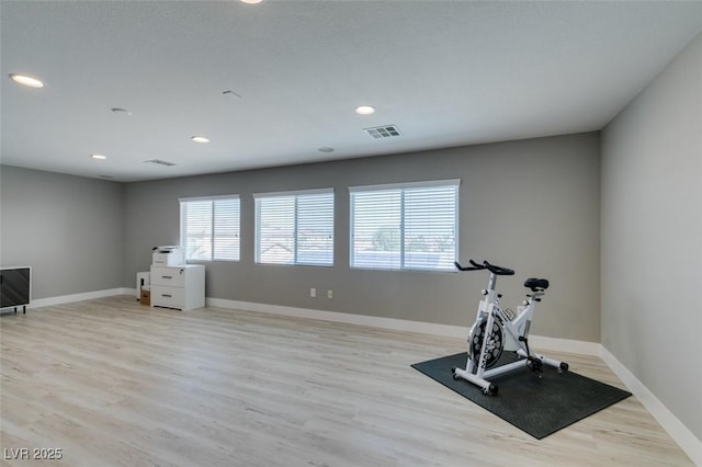 workout area featuring a healthy amount of sunlight, baseboards, visible vents, and light wood-style flooring