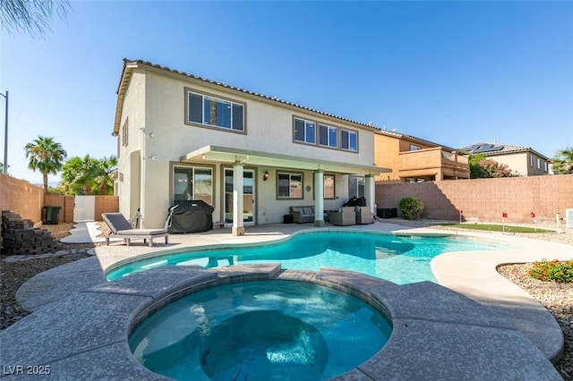 back of property with a pool with connected hot tub, stucco siding, and a patio