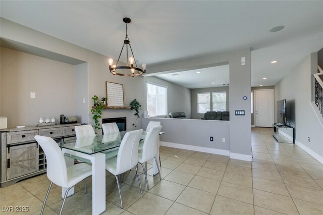 dining area with light tile patterned floors, baseboards, an inviting chandelier, a fireplace, and recessed lighting