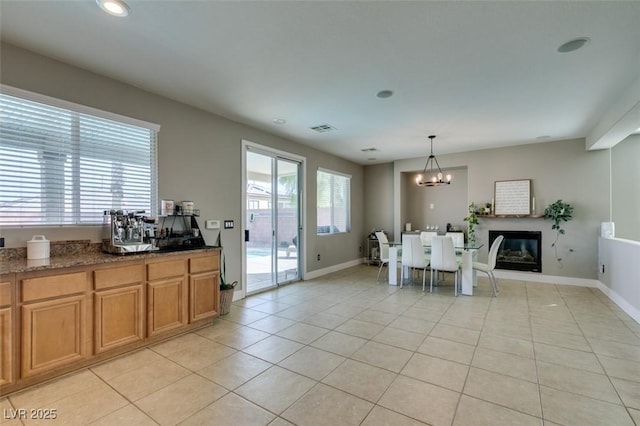 dining space with light tile patterned flooring, a chandelier, recessed lighting, baseboards, and a glass covered fireplace