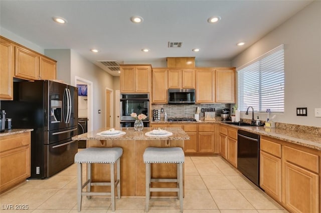 kitchen with stainless steel appliances, a sink, decorative backsplash, a breakfast bar, and a kitchen island