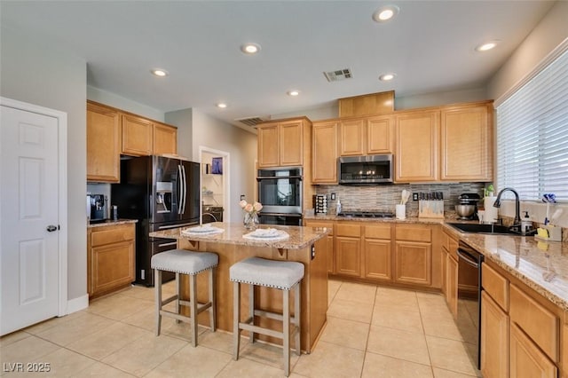 kitchen with a kitchen island with sink, stainless steel appliances, a breakfast bar, a sink, and visible vents