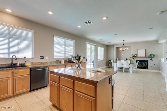 kitchen featuring a center island, visible vents, light tile patterned flooring, a sink, and dishwashing machine