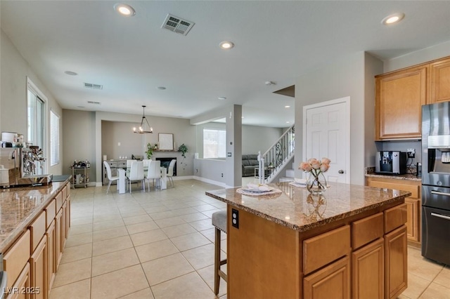 kitchen featuring fridge with ice dispenser, recessed lighting, a kitchen island, light stone countertops, and light tile patterned flooring